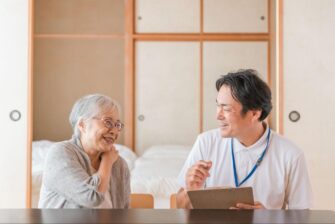 高齢の患者さんの自宅で口腔ケア・問診を行う訪問歯科医の画像