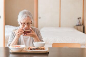 笑顔で食事をするシニア女性の画像