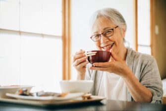 誤嚥性肺炎に注意しつつ笑顔で食事をする高齢女性