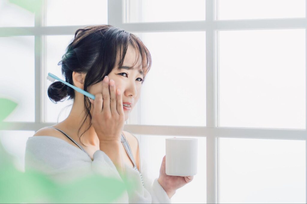 親知らずが痛み頬を押さえる歯磨き中の女性