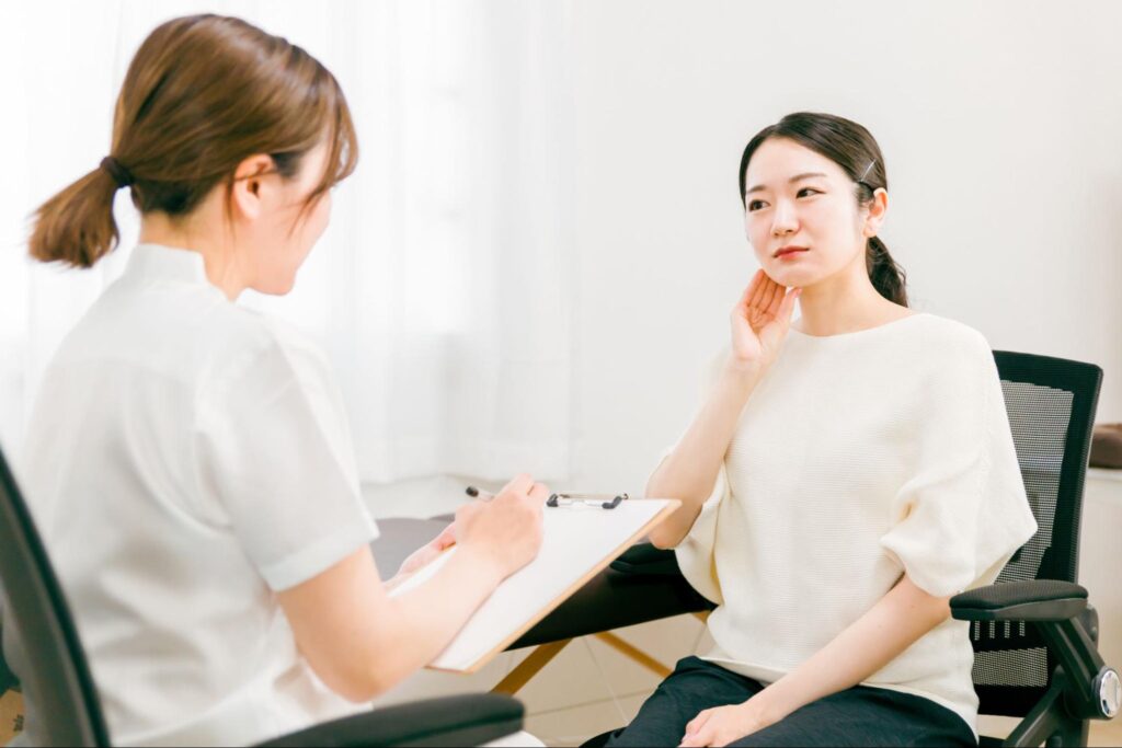顎関節症について医師に症状などを話している女性患者