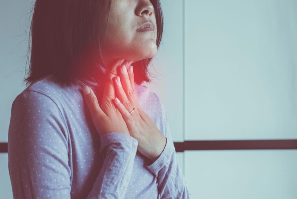 嚥下時に音が鳴る違和感を感じて喉を押さえている女性の画像
