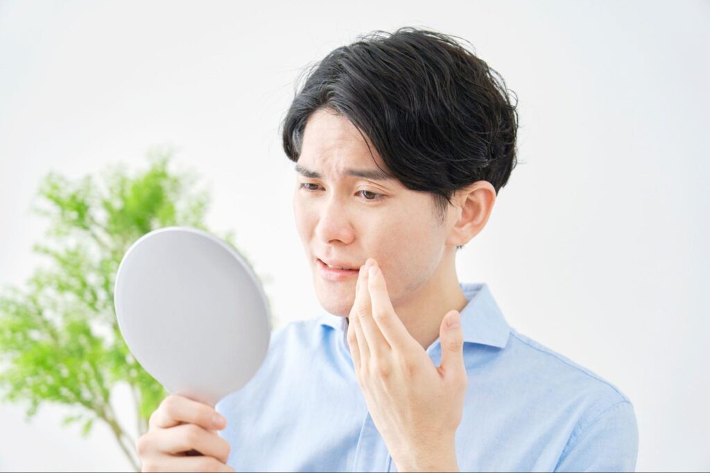 抜歯に不安があり、不安そうな顔で鏡を見ている男性