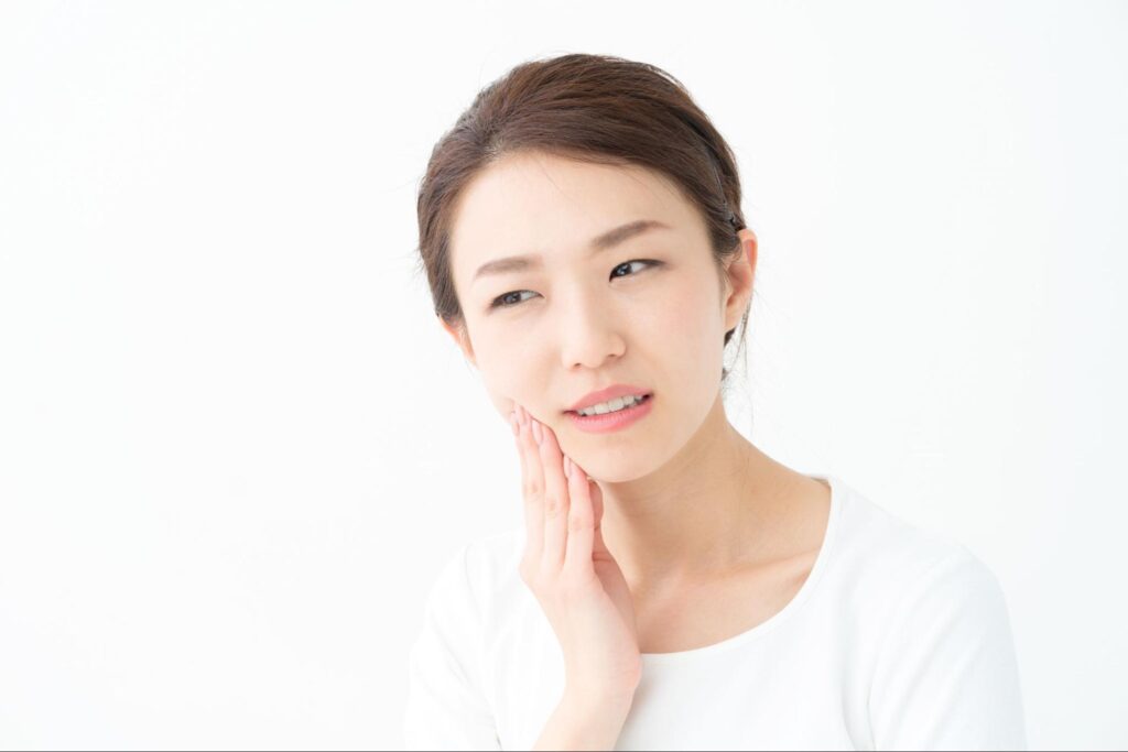 顎関節症による痛みや違和感があり顎を押さえる女性