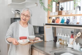 食事ののったトレーを持った高齢女性