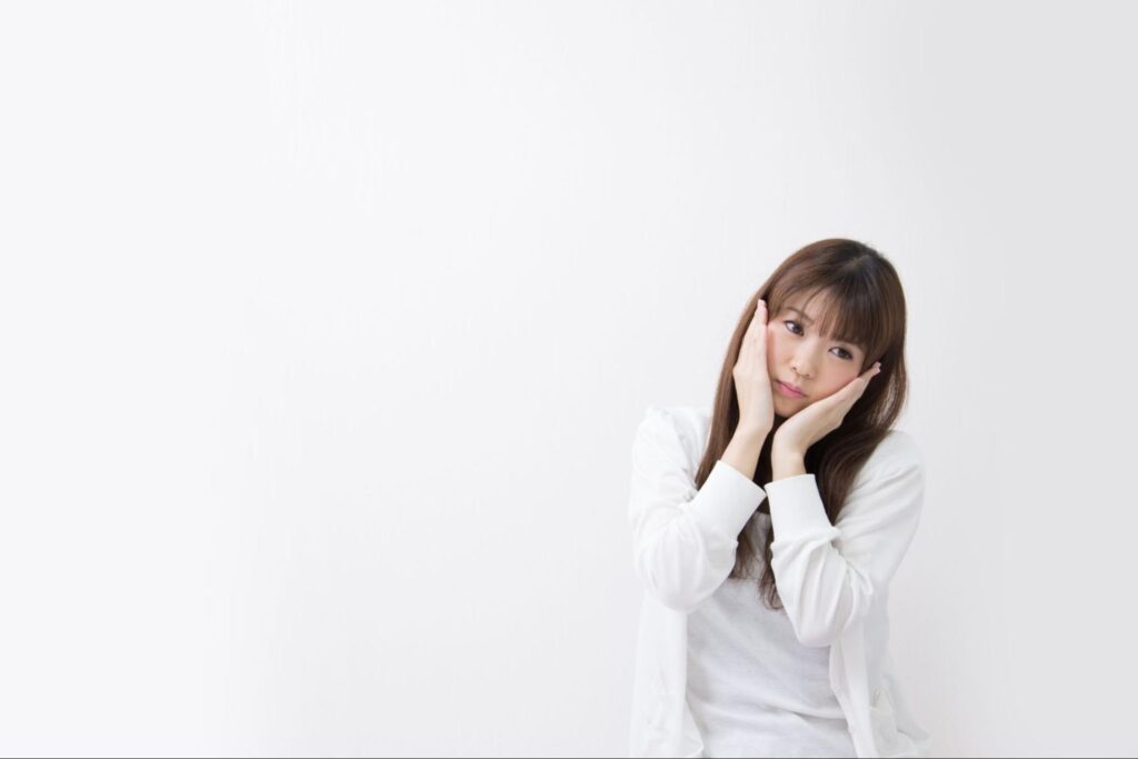 頬を押さえて首を傾ける女性