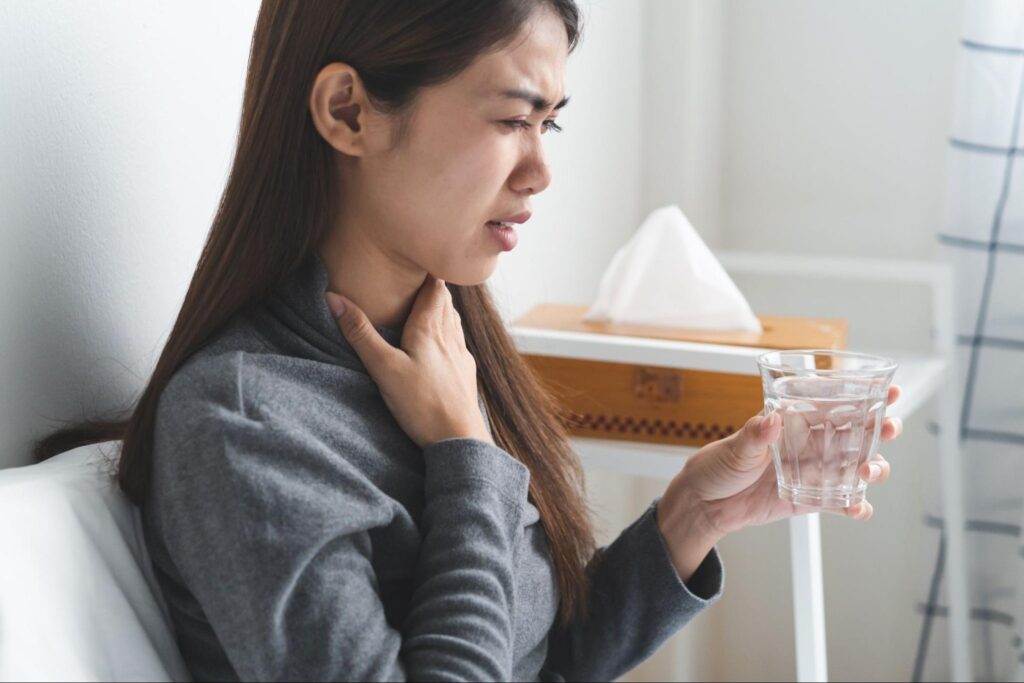 苦しそうな顔で喉元を押さえる女性