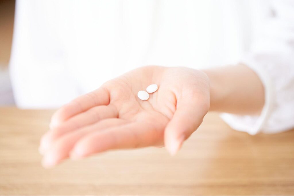 抗生物質や鎮痛剤を飲もうとしている人の手