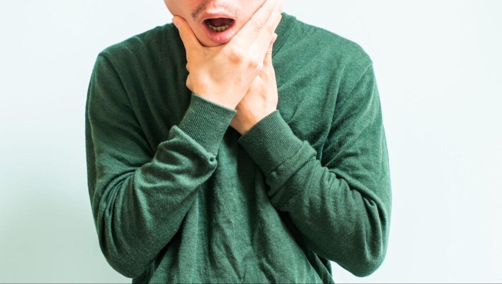顎関節症による痛みや違和感で顎を押さえる男性