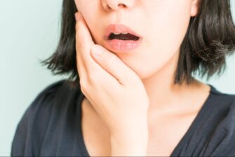 顎を押さえる顎関節症の女性
