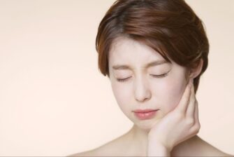 顎関節症による痛みや違和感があり顎を押さえて顔をしかめる女性